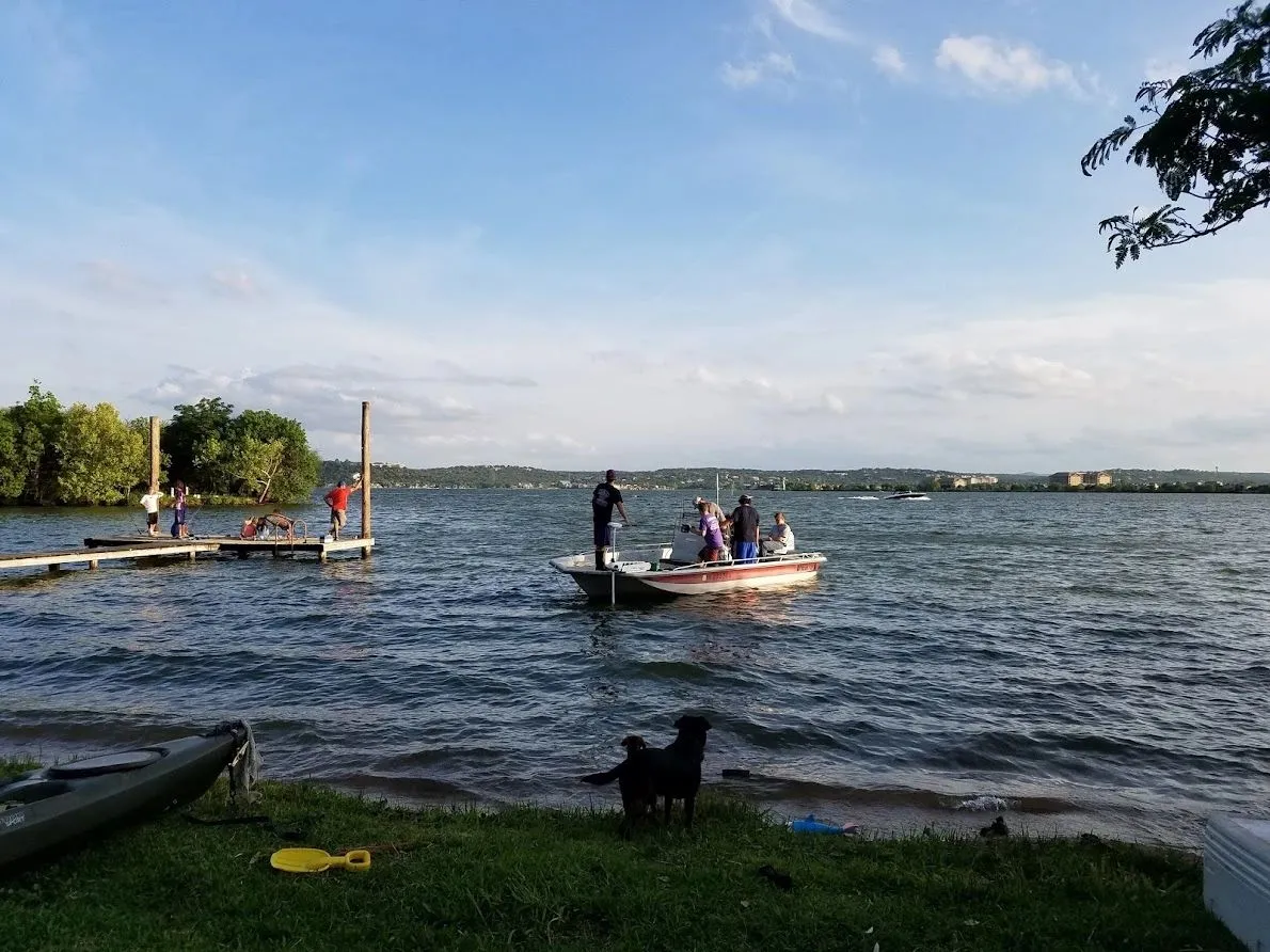 A family fishing from a boat beside a private dock on Lake LBJ at golden hour