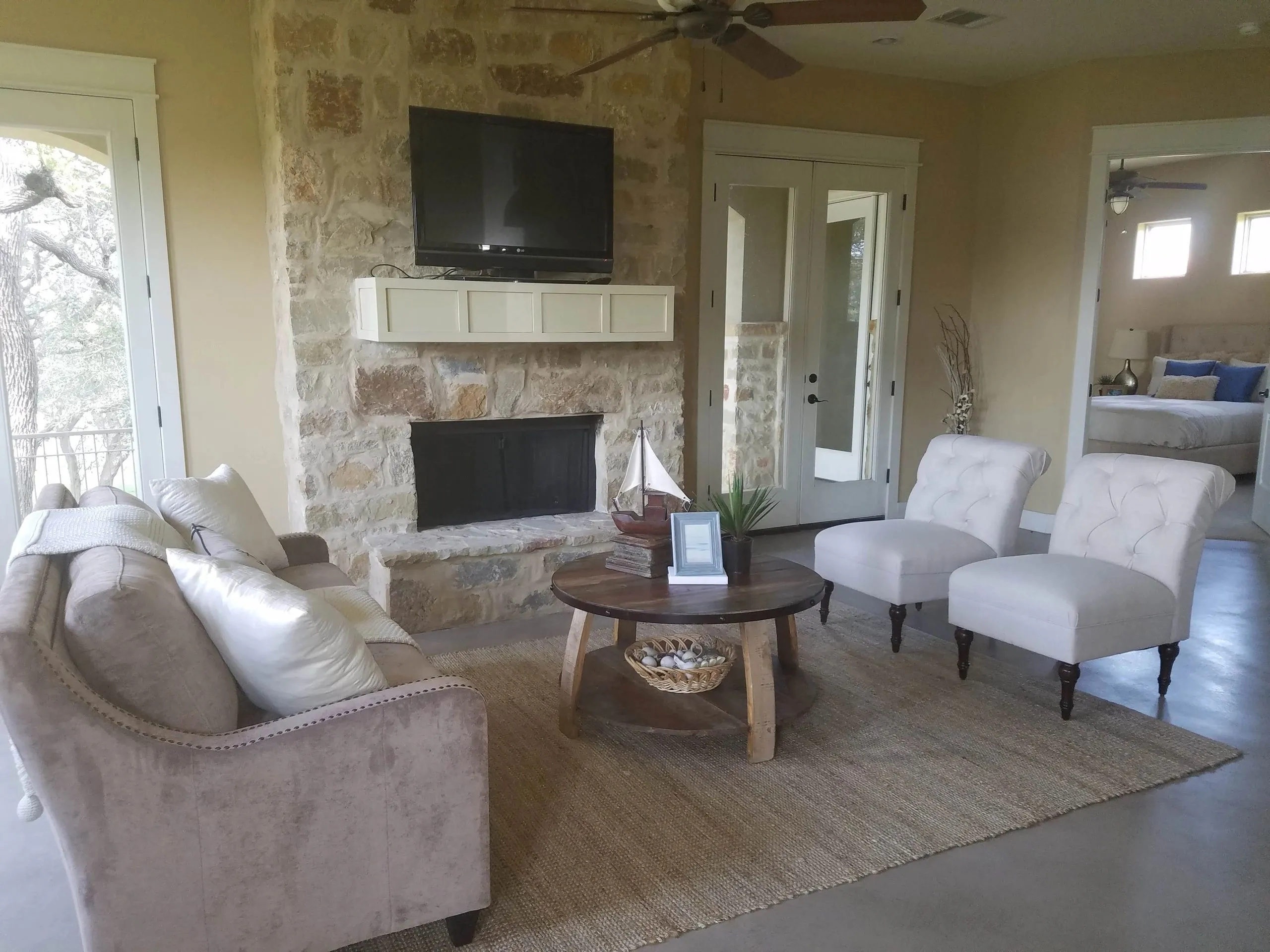 Living room of a Hill Country lake house with a limestone fireplace, ready for the owners' arrival